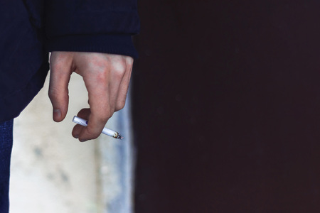 Young man's hand holding a cigarette with smoke Harm of smoking Close up Copy spaceの写真素材