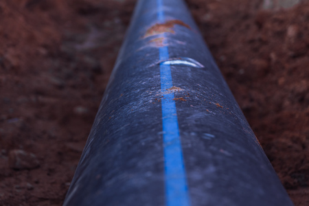 Plastic water pipe is in the trench in the direction under a blue sky residential buildingsの写真素材