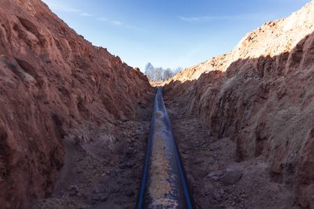 Plastic water pipe is in the trench in the direction under a blue sky residential buildingsの写真素材