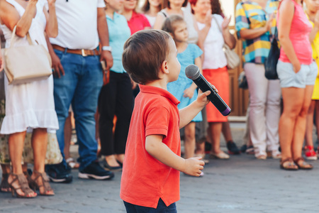 August 4, 2018 Street festivities in the evening city A little boy with a microphone stands on the street in front of people.のeditorial素材