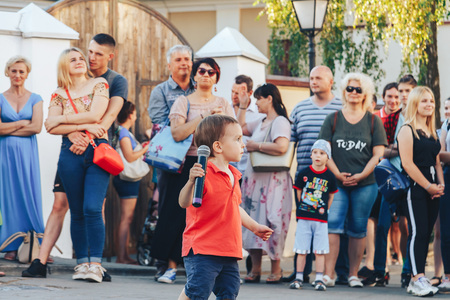August 4, 2018 Street festivities in the evening city A little boy with a microphone stands in front of people at a street concert.のeditorial素材