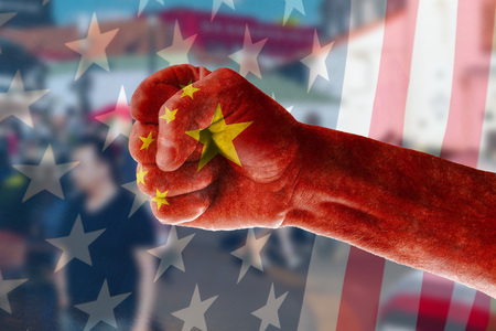 China's expansion into the US market Concept of a man's hand painted in the colors of the flag of China on the background of street trading in the blur and the US flag.の写真素材