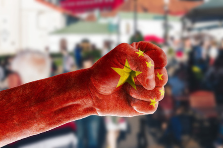 China's expansion into the markets of the world The concept of a man's hand painted in the colors of the flag of China against the background of street trading in blur.の写真素材