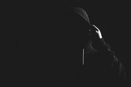 Angry man standing in a hood in the dark. Street violence.の写真素材
