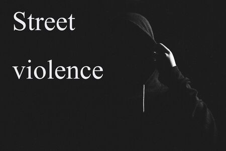 Angry man standing in a hood in the dark. Street violence. Written inscription Street violenceの写真素材