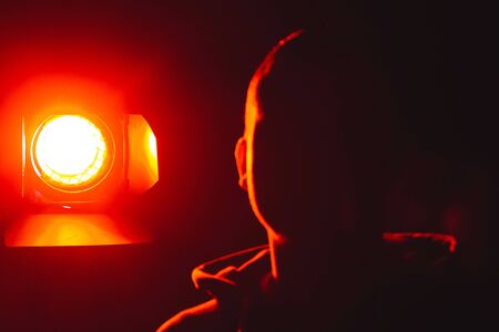 The guy standing next to a luminous spotlight on the streetの写真素材