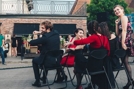 May 25, 2019 Minsk Belarus Street festivities in the evening city A man and several girls laugh when they pretend to go by car sitting on chairs in the squareのeditorial素材