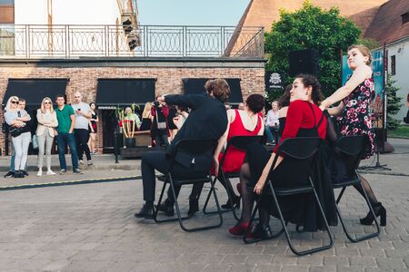 May 25, 2019 Minsk Belarus Street festivities in the evening city Happy artists laugh when they pretend to go by car sitting on chairs in the squareのeditorial素材