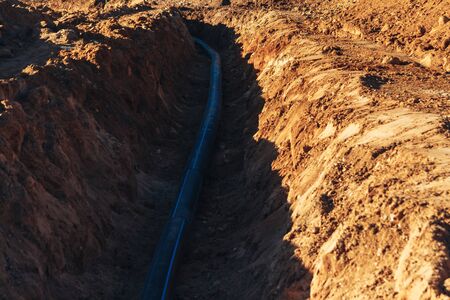 Plastic water pipe is in the trench in the direction under a blue sky residential buildingsの写真素材