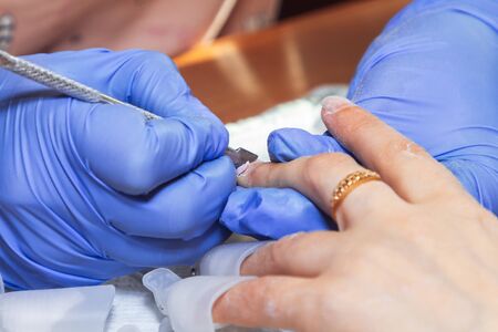 Manicurist processes nails with a scraper for manicure at home Development of private business in...