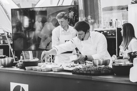 June 1, 2019 Festivities in the city on the day of Swedish culture Chef prepares food at a public master class Assistants stand nearby Black and white imageのeditorial素材