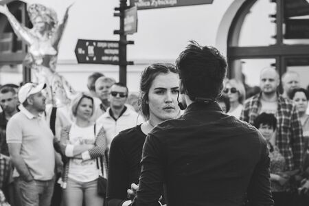 May 25, 2019 Minsk Belarus Street festivities in the evening city Girl and man show a theatrical performance with a band in front of people on the street. Black and white imageのeditorial素材