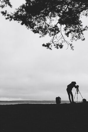 Silhouette Photographer sets a tripod on the lake Black and white imageの写真素材
