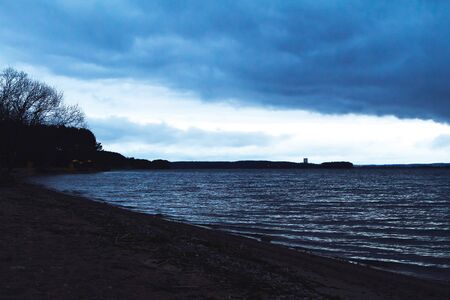 The shore of the lake in the early morning in cloudy weatherの写真素材