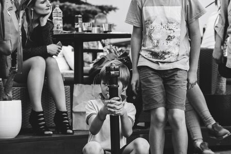 May 25, 2019 Minsk Belarus Street festivities in the evening city The boy holds on to a fence post among people on the street. Black and white imageのeditorial素材