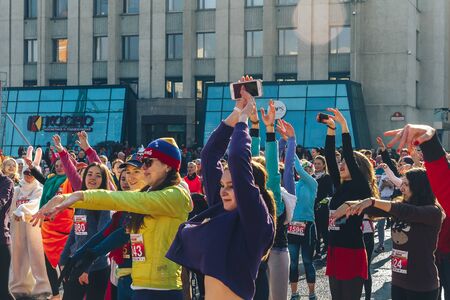 March 8, 2019 Minsk Belarus Women's Day Race on March 8 Women do warm-ups near the stage before the race on the squareのeditorial素材