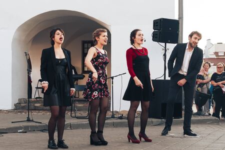 May 25, 2019 Minsk Belarus Street festivities in the evening city A man and three girls actors sing in front of people in the square.のeditorial素材