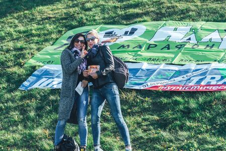 October 6, 2018 Novogrudok Belarus Castle Road Two women stand near a poster lying on the grassのeditorial素材