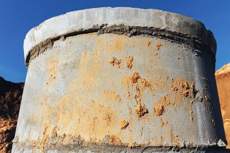 Construction site concrete well for water pipes and sewage sprinkled with earth