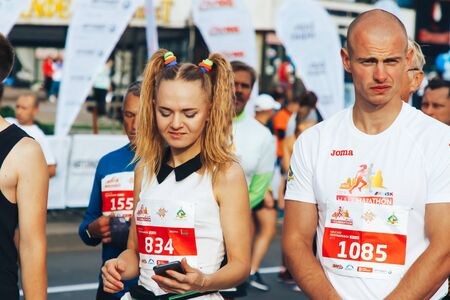 September 15, 2018 Minsk Belarus Half Marathon Minsk 2019 Beautiful girl marathon runner looks at the phone among athletes before startingのeditorial素材