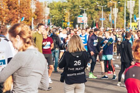 September 15, 2018 Minsk Belarus Half Marathon Minsk 2019 Woman photographer takes pictures on camera as athletes gather on the road before the raceのeditorial素材