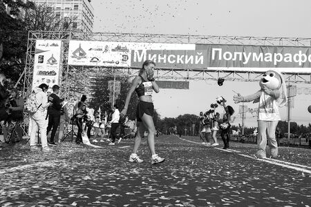 September 15, 2018 Minsk Belarus Half Marathon Minsk 2019 Woman walks after she finishes marathon. Confetti flies in the air in black and whiteのeditorial素材
