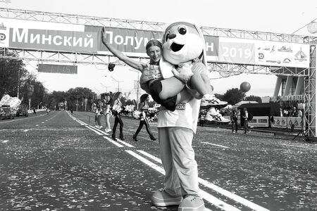 September 15, 2018 Minsk Belarus Half Marathon Minsk 2019 Woman athlete laughs when a man in a hare costume lifted her in black and whiteのeditorial素材