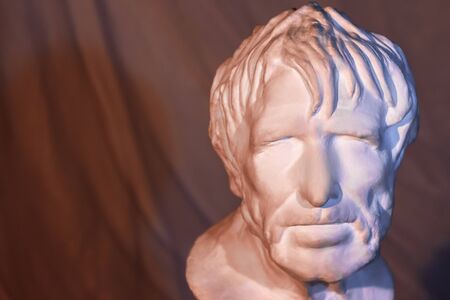 Gypsum copy of ancient statue Seneca head on dark textured background. Male ancient gypsum portrait...