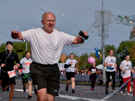 September 15, 2019 Minsk Belarus Half Marathon Minsk 2019 Athlete with glasses with a phone crosses the finish line of the marathonのeditorial素材