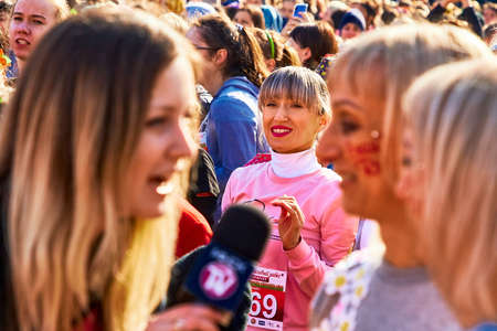 March 8, 2019 Minsk Belarus Pretty smiling happy girl stands at a street concert. View through a girl correspondent interviews a woman with the the inscription, beauty run in blurのeditorial素材