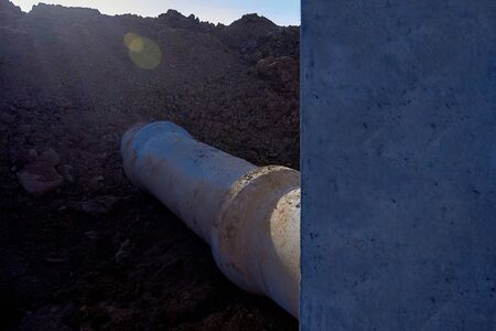 Storm sewage inlet with a pipe connected to it for water drainage during construction View against the sunの写真素材