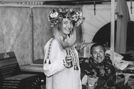 July 6-7, 2019 Village Petrevichi Minsk region Belarus Beetle trail 12 Midsummer In the black and white image, a young woman wearing a wreath of flowers stands in a tent next to a happy manのeditorial素材