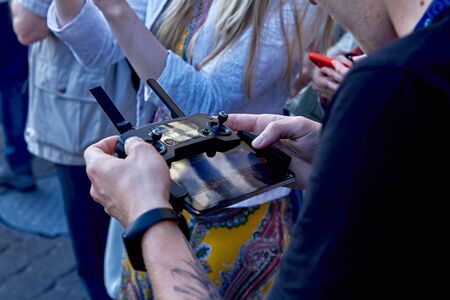 The guy controls the quadrocopter from the remote control among people