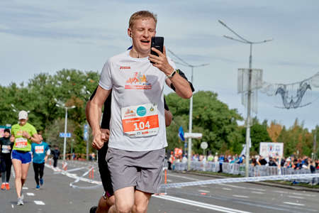 September 15, 2019 Minsk Belarus A marathon race in which a happy athlete with a phone in his hand...