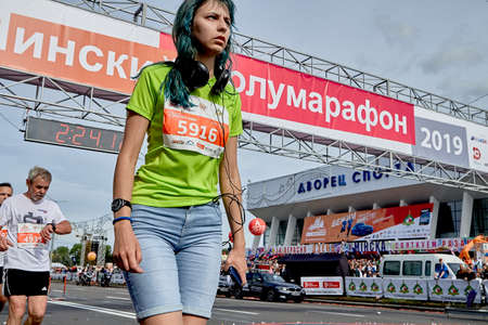 September 15, 2019 Minsk Belarus A close up of a tired woman with headphones and a phone crossed the finish lineのeditorial素材