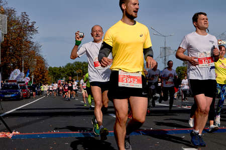September 15, 2019 Minsk Belarus Half Marathon Minsk 2019 Crowd runners crossing the finish line marathon on paved road in town. Mature athlete runs with a cameraのeditorial素材