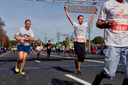 Half Marathon Minsk 2019 Competitor crossing the finish line celebrating with arms raisedのeditorial素材