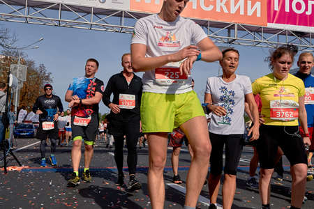 September 15, 2018 Minsk Belarus Half Marathon Minsk 2019 Cropped photo, marathon runners crossing the finish line on paved road in town. Athlete looks at the clock crossing the finish line.のeditorial素材