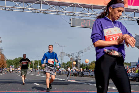 September 15, 2019 Minsk Belarus Unidentified people crossing the finish line in the marathon. Female athlete looks at watch crossing the finish line.のeditorial素材
