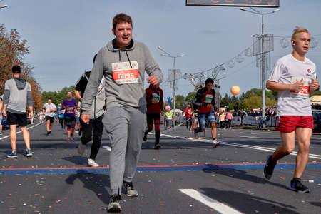 September 15, 2018 Minsk Belarus Half Marathon Minsk 2019 Group of runners cross the finish line marathon on paved road in town. Emotional man crossed the finish line of the marathonのeditorial素材
