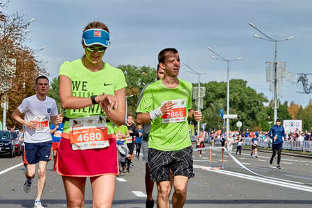 September 15, 2018 Minsk Belarus Half Marathon Minsk 2019. Participants of the marathon crossing the finish line.Woman runner checking her running time from smart watch at the marathonのeditorial素材