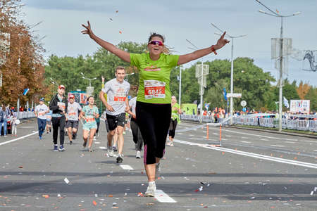 September 15, 2019 Minsk Belarus A happy woman runs a marathon celebrating with her arms raisedのeditorial素材