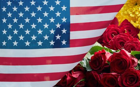 An American flag with rose behind waving in the wind. American flag,the symbolic of liberty,freedom,patriotic,honor,american family,nation,independence day,4th of July,labor dayの写真素材