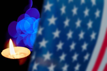 A candle burning on the background of blurry purple lights. American flag in blur before a candleの写真素材