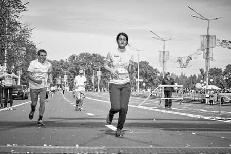 September 15, 2019 Minsk Belarus In black and white, a tired woman crosses the finish line ahead of an athleteのeditorial素材