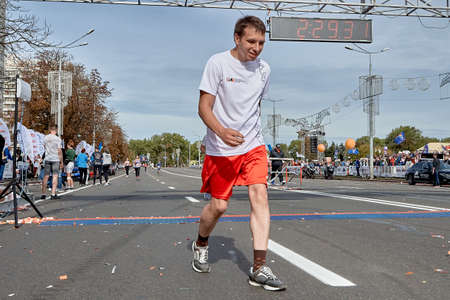 September 15, 2019 Minsk Belarus A tired athlete crossed the finish line of the marathon on a city roadのeditorial素材