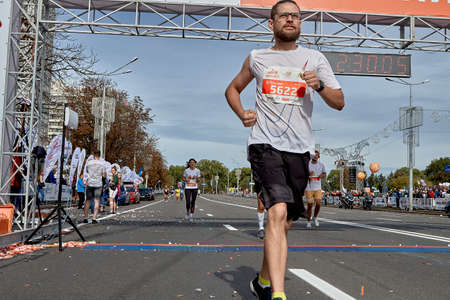 September 15, 2019 Minsk Belarus Close-up of athlete in glasses crossing the finish line of a marathon on a city roadのeditorial素材
