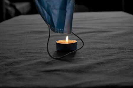 Abstract image a candle flame touches a protective mask