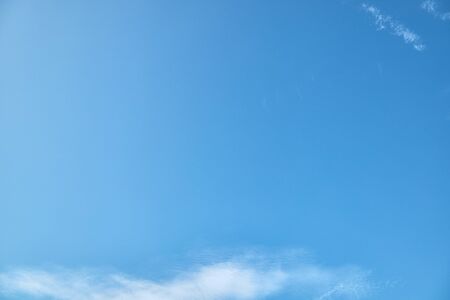 Blue background made of summer clear sky with beautiful natural white cloudsの写真素材