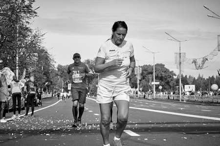 September 15, 2019 Minsk Belarus In the black and white close up image not a young woman runs to the finish line of the marathonのeditorial素材